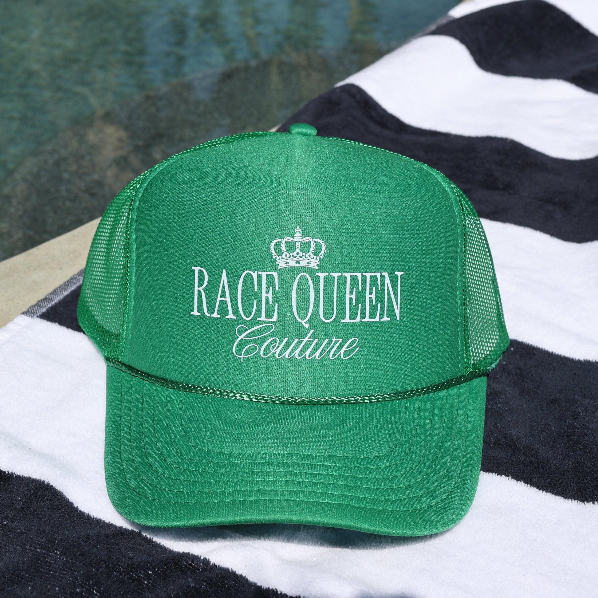 Green RQC Trucker Hat on a black adn whit striped towel
