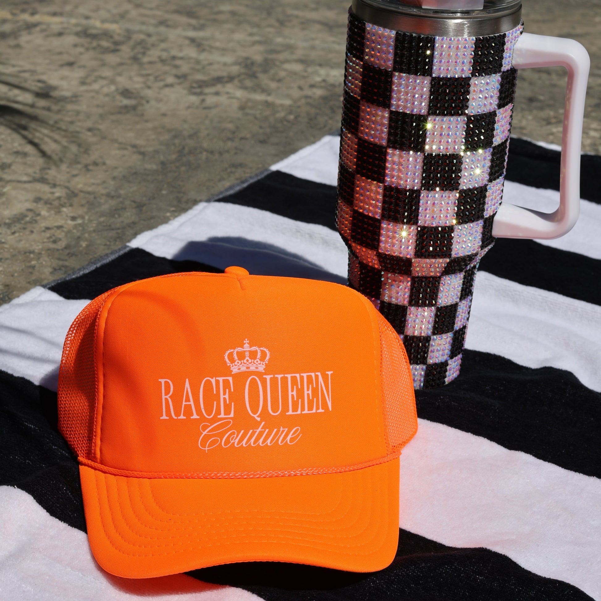 Neon Orange RQC Trucker Hat on a black and white striped towel