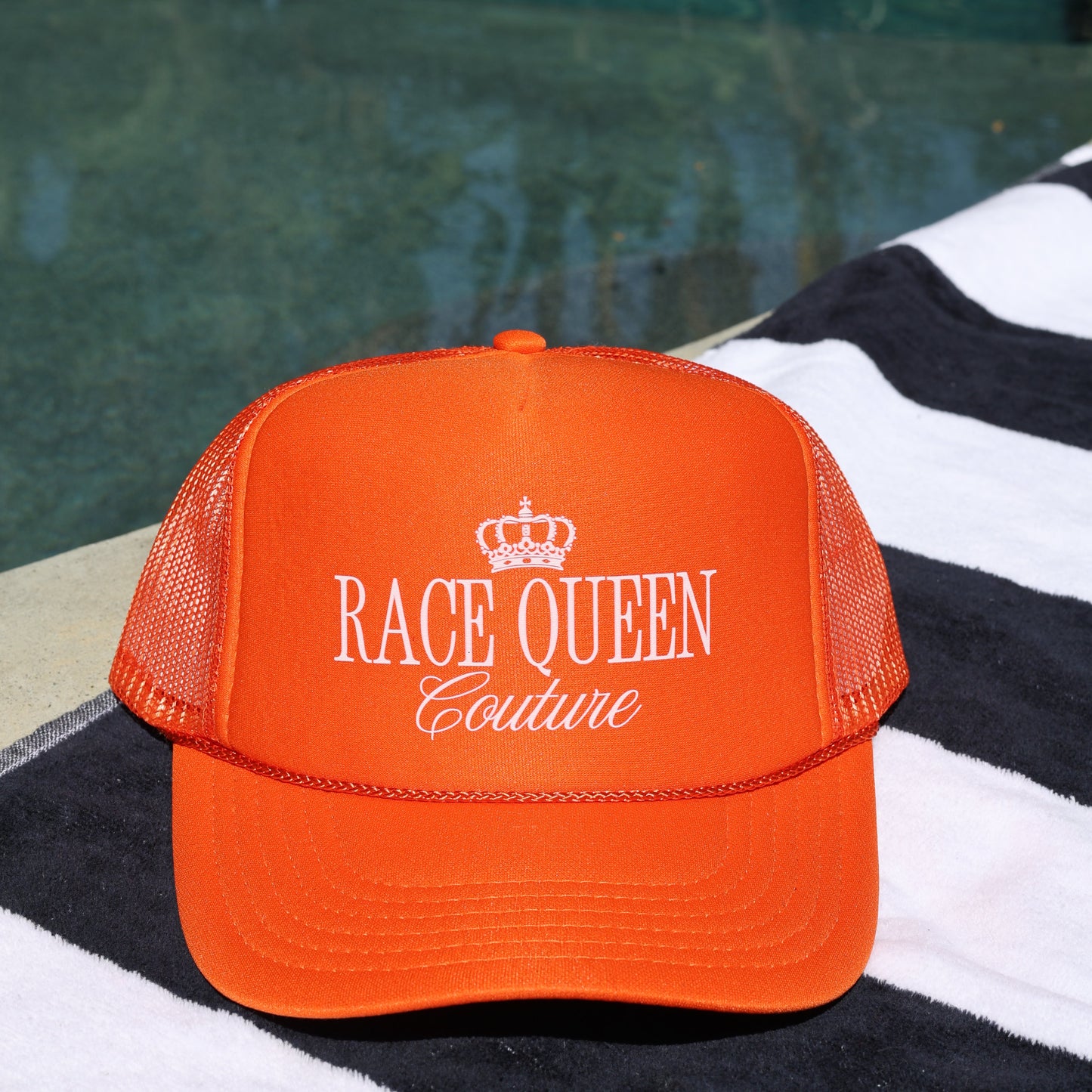 Orange cap with 'Race Queen Couture' text on a black and white striped fabric background