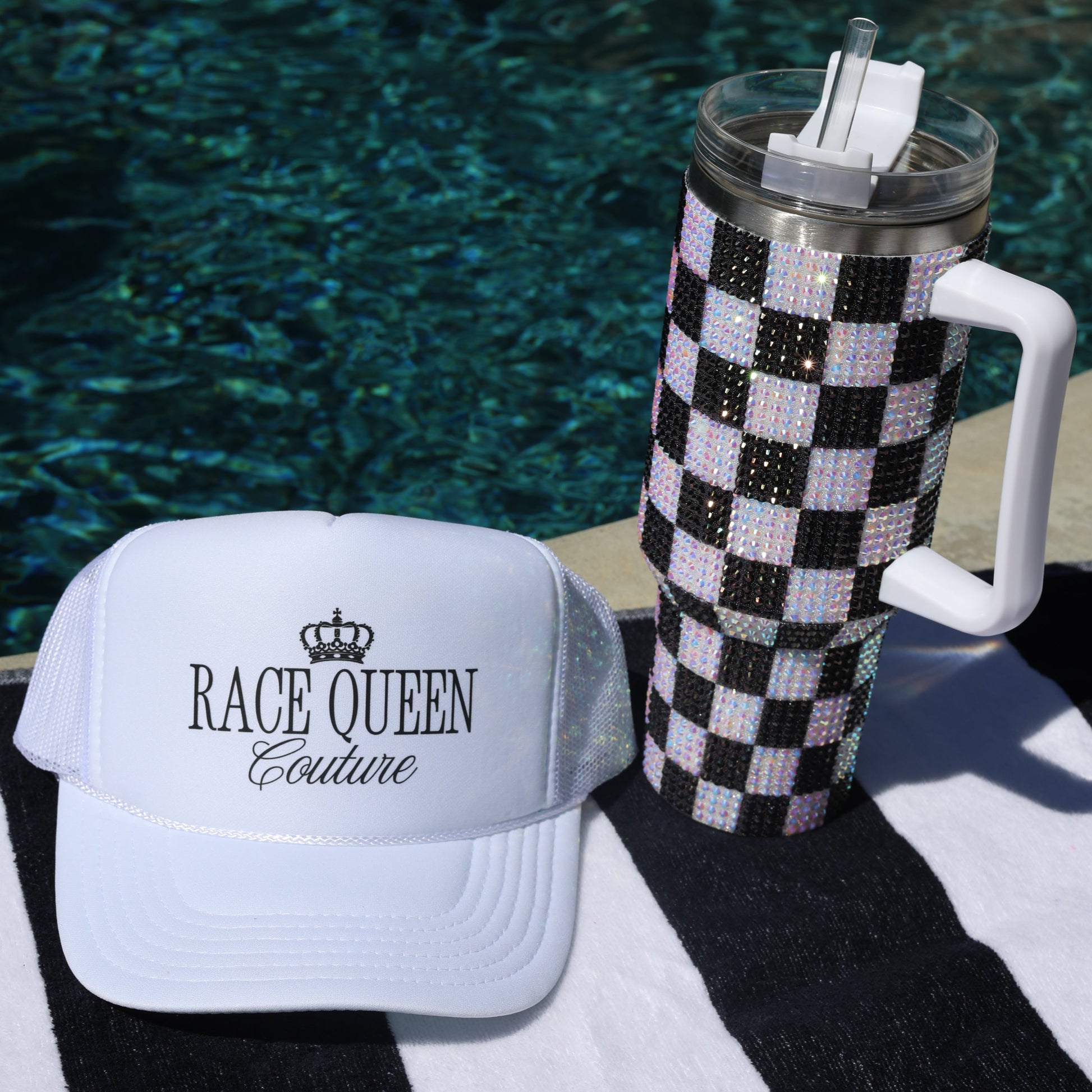 Checkered tumbler with decorative lid on towel with 'Race Queen COuture'  branding on white hat